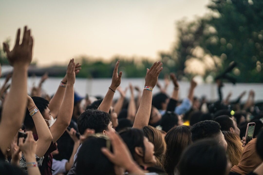 Crowd at a live music concert with hands raised and stage lights